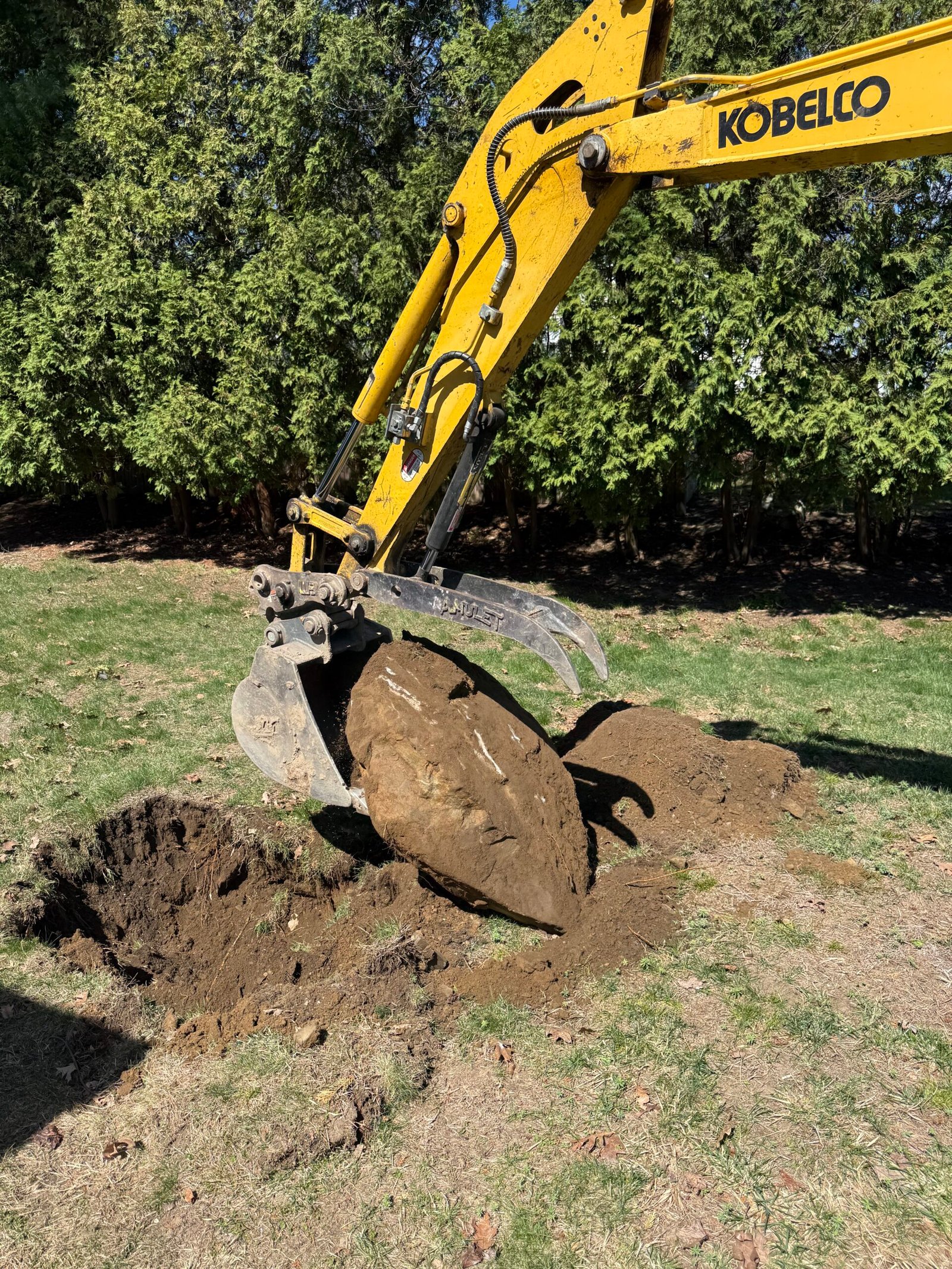 Excavator bucket digging soil for a landscaping installation