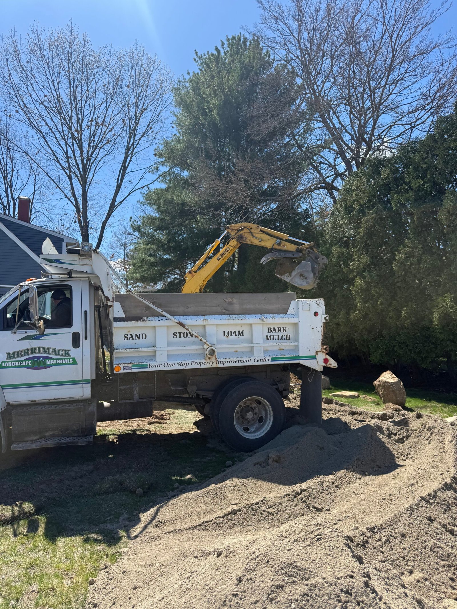 Excavator and dump truck at a residential job site