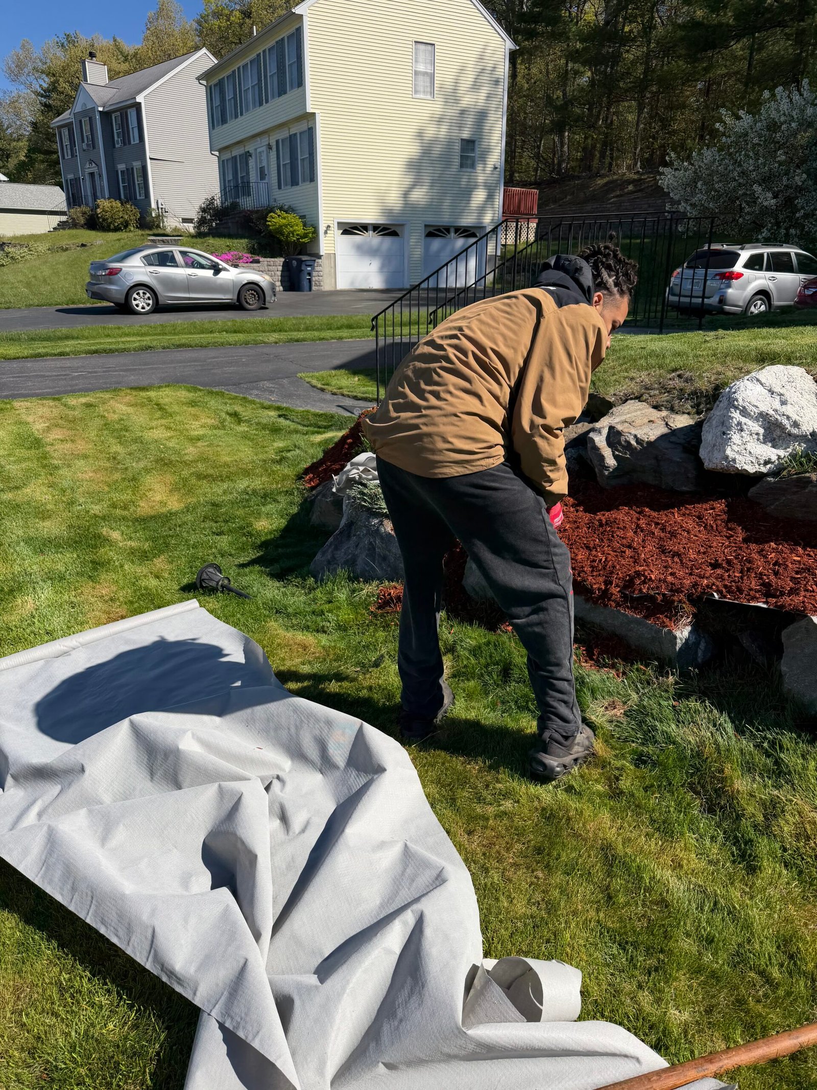 Landscaper spreading red mulch in a residential yard